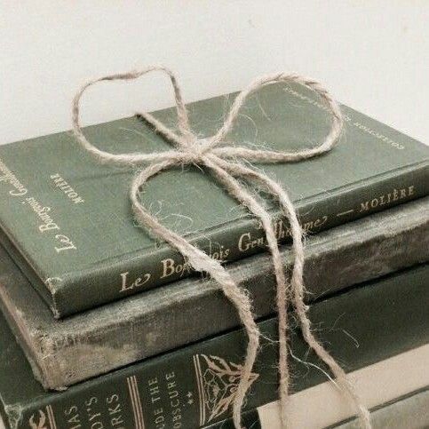 three books stacked on top of each other with a string tied to the book ends