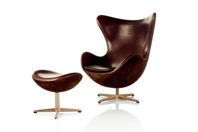 an egg chair and ottoman are shown in brown leather, with the foot rest extended