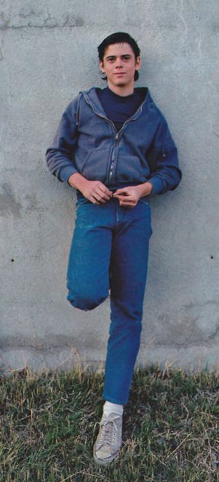 a young man leaning against a concrete wall