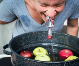 a man drinking water from a bottle in a bucket filled with apples