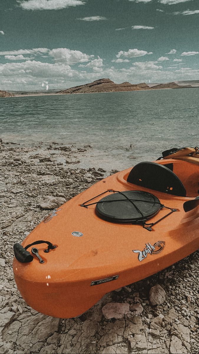 an orange kayak sitting on top of a rocky beach