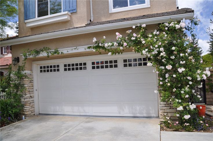 a white garage with roses growing on the side