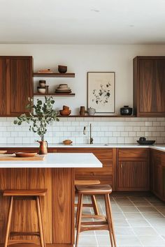 a kitchen with wooden cabinets and stools in front of the counter top, along with white tile flooring