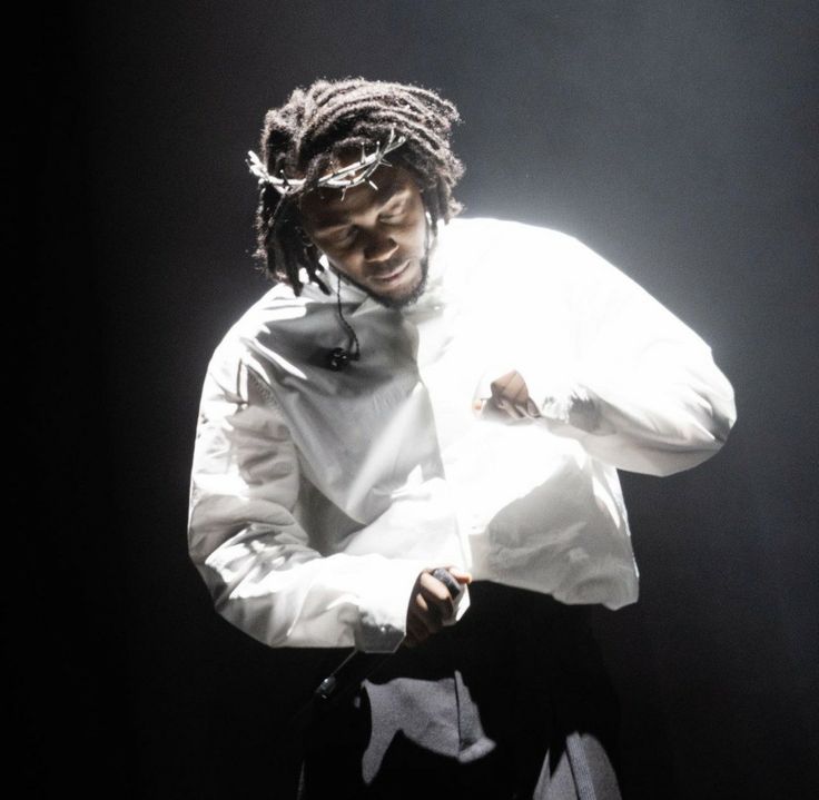 a man with dreadlocks standing in front of a black background