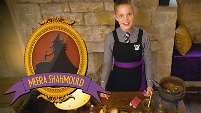 a woman in an apron standing next to a table with food and wine on it