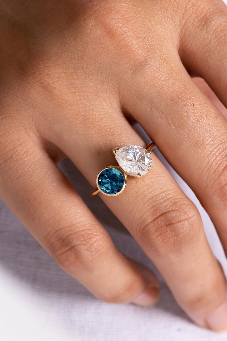 a woman's hand wearing a gold ring with blue and white stones