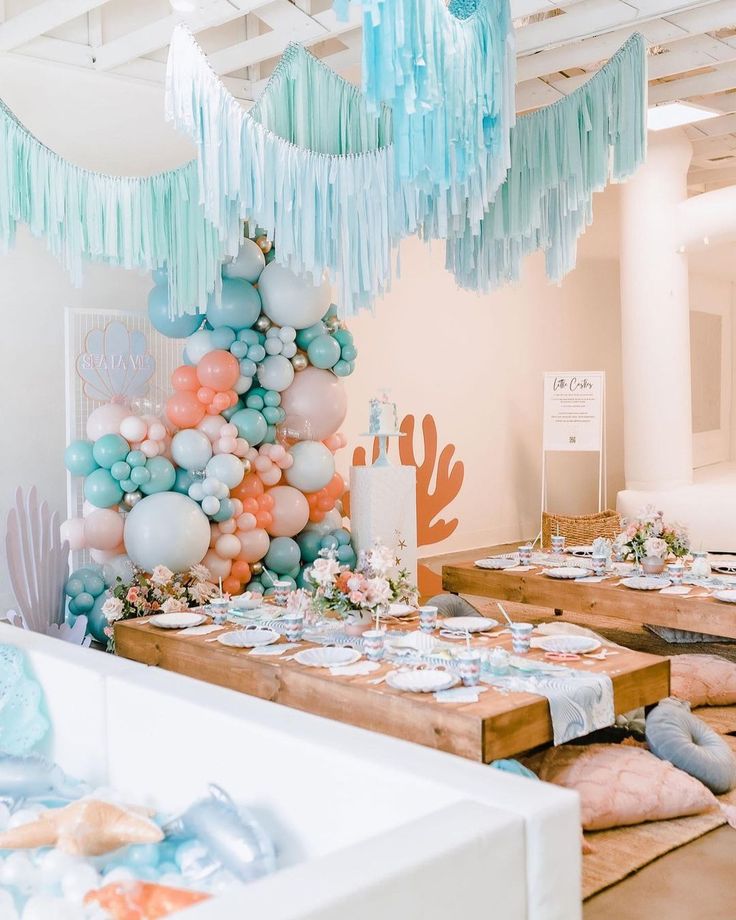 the table is set up with balloons, plates and napkins for an ocean themed party