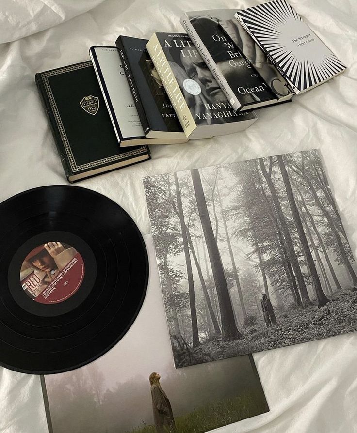 an open book and some black records on a white sheet with trees in the background