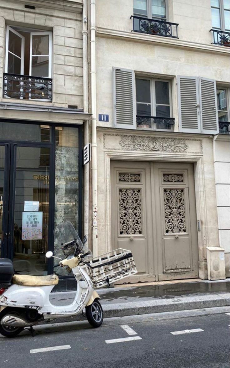 a motor scooter parked in front of a building with shutters on the windows