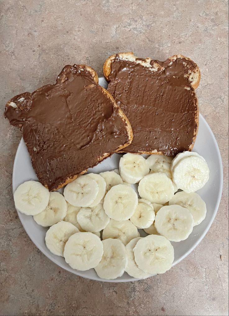 peanut butter and banana slices are on a plate with bread cut in half to look like they're ready to eat