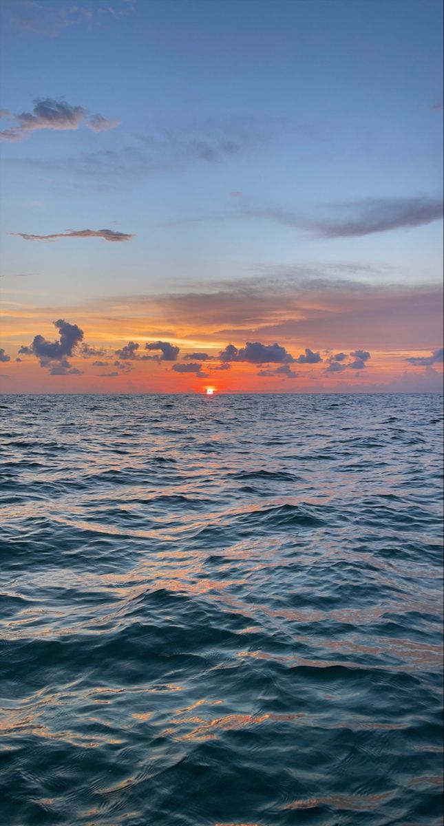 the sun is setting over the ocean as seen from a boat in the water with waves