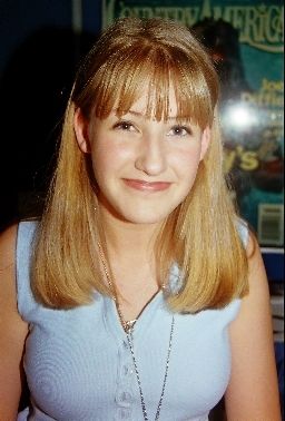 a woman with blonde hair and blue dress posing for a photo in front of a movie poster