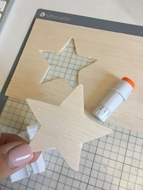 someone is making a wooden star decoration with glue