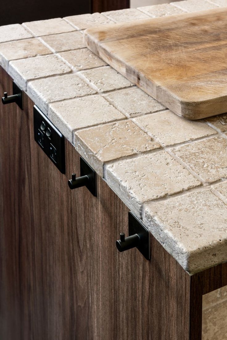 a wooden cutting board sitting on top of a counter next to a tile backsplash