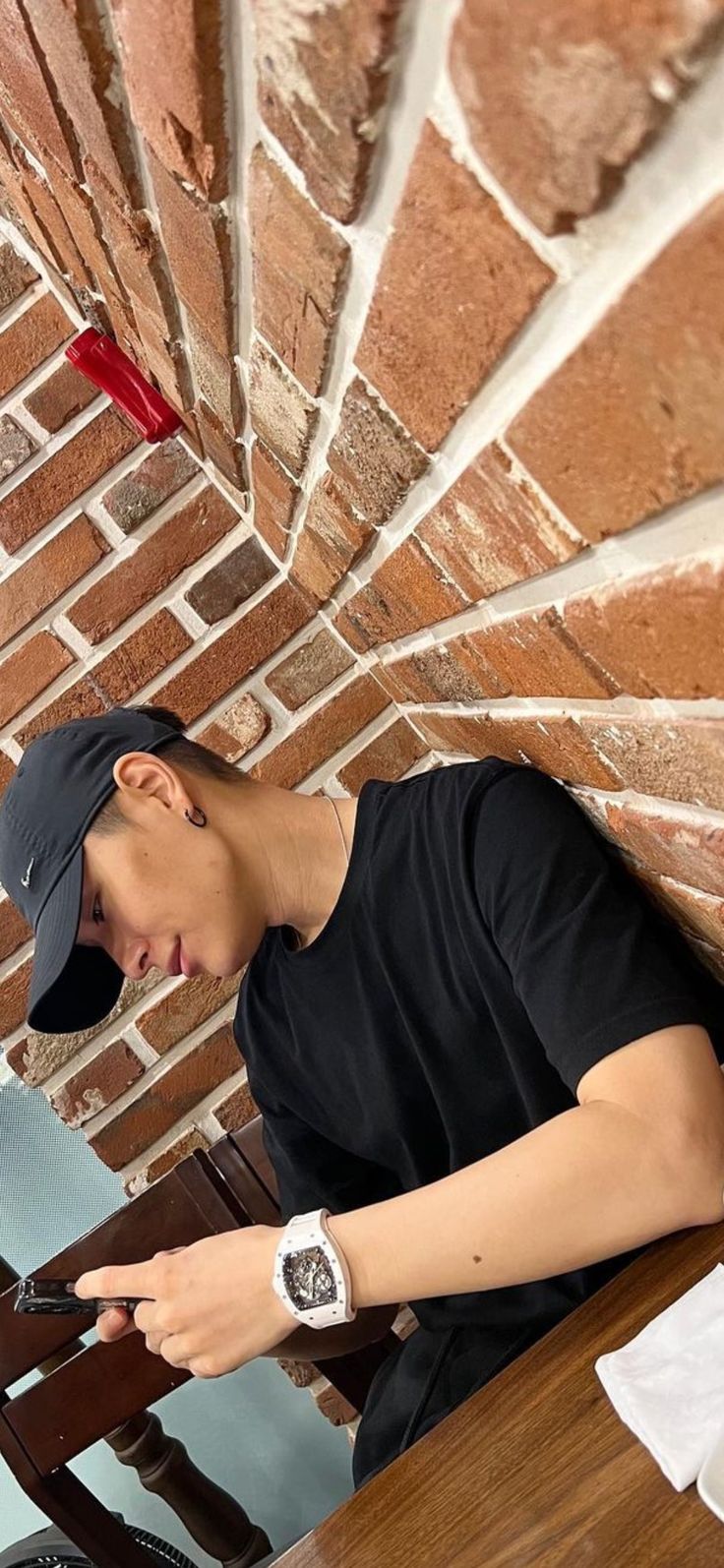 a young man sitting at a table using his cell phone