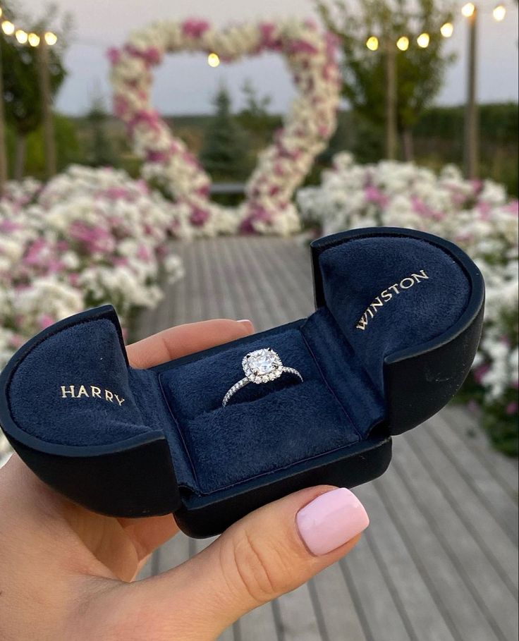 someone is holding up their engagement ring in a velvet box with the word happy written on it