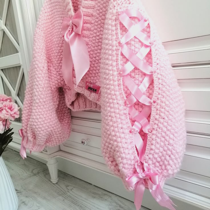 a pink sweater hanging on the wall next to flowers