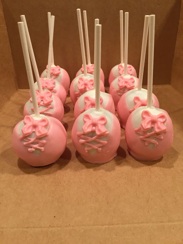 pink and white cake pops are arranged in a row on a brown paper bag with sticks sticking out of them