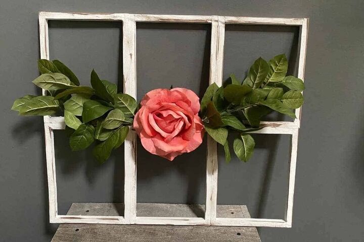 an old window frame is decorated with fake flowers and greenery on the top shelf