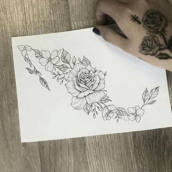 a hand holding a piece of paper with flowers on it and leaves around the edge