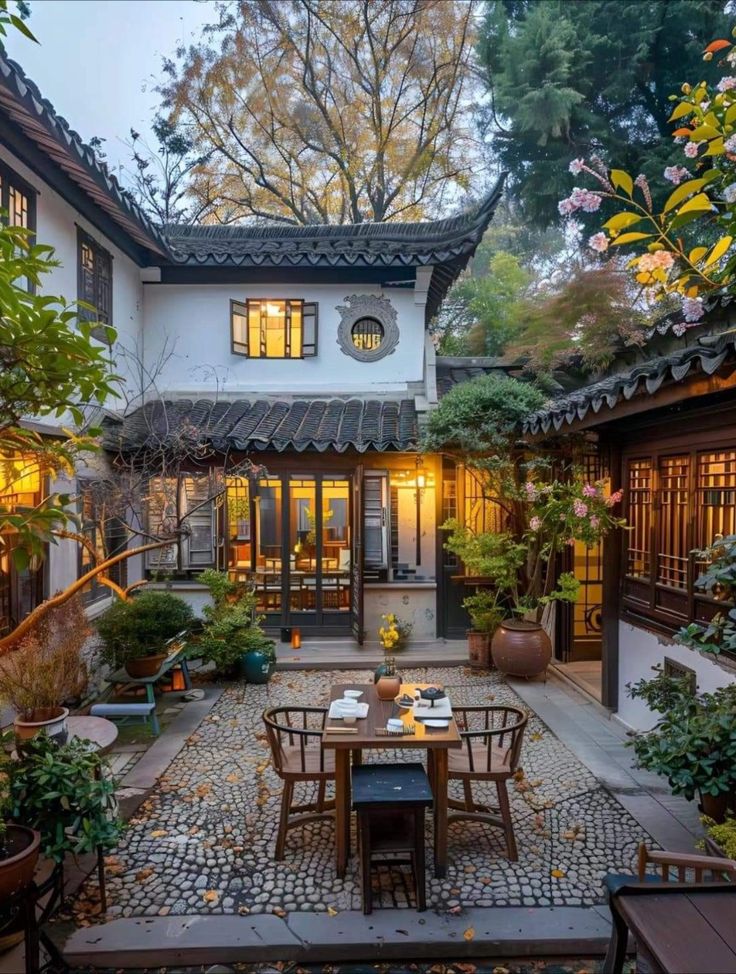 an outdoor dining area in the middle of a courtyard with potted plants on either side