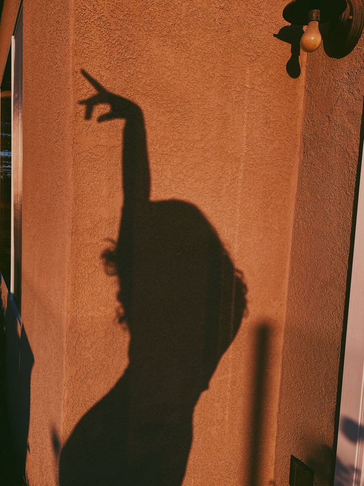 the shadow of a skateboarder is cast on a wall by a building with a door