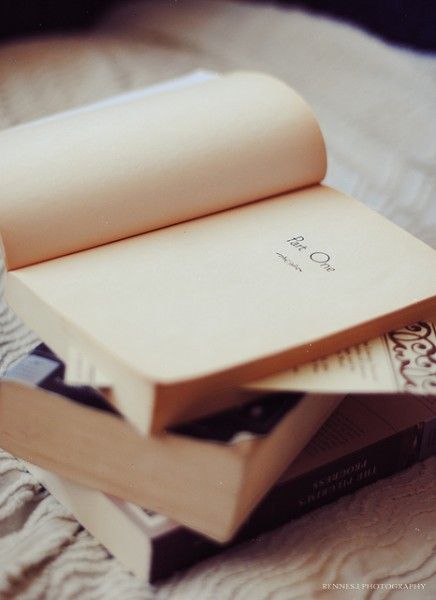 an open book sitting on top of a bed next to a cup