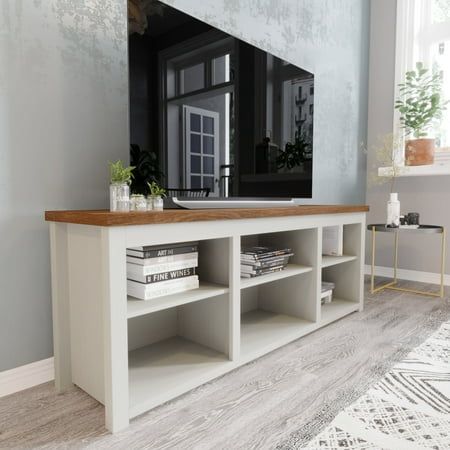 a living room with a large tv on top of a wooden shelf next to a window