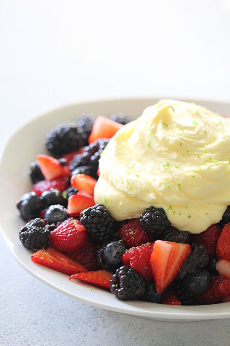 berries and cream in a white bowl on a table