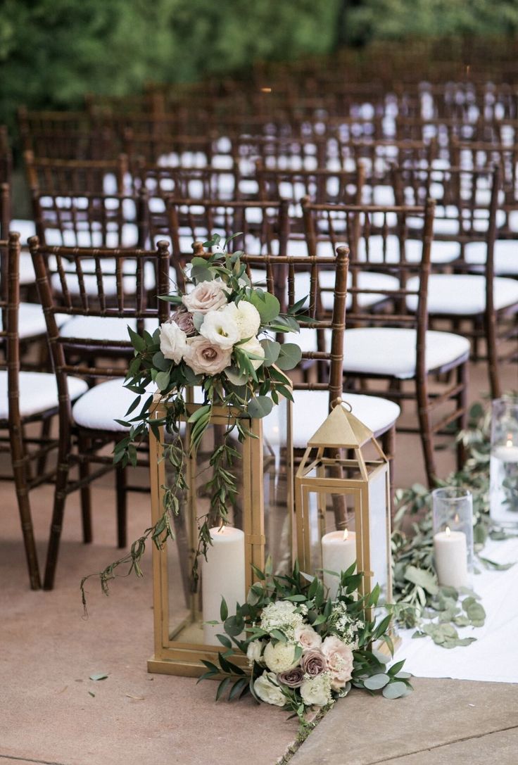 an arrangement of candles, flowers and greenery are on the table at this outdoor wedding