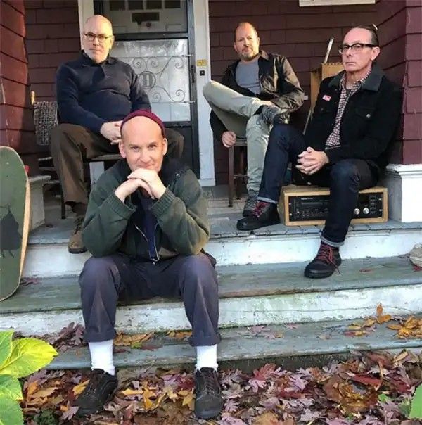 three men sitting on the steps in front of a house with their feet propped up