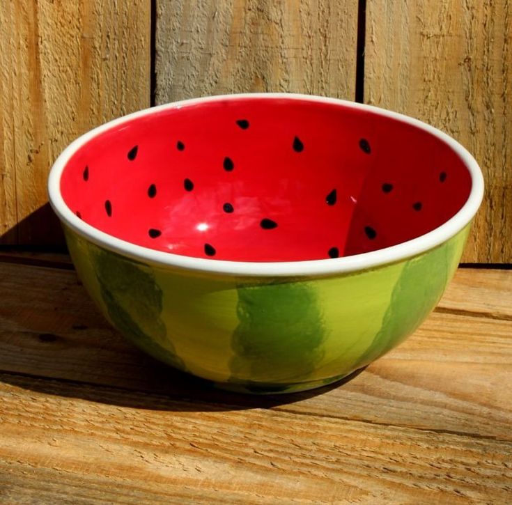 a watermelon painted bowl sitting on top of a wooden table