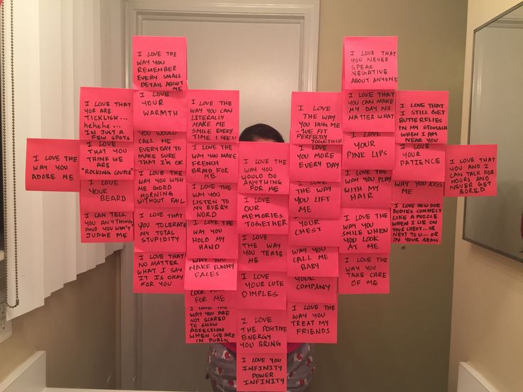 a person standing in front of a mirror covered in pink post it notes with words written on them