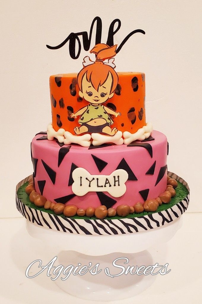 a pink and black cake sitting on top of a white table next to a sign