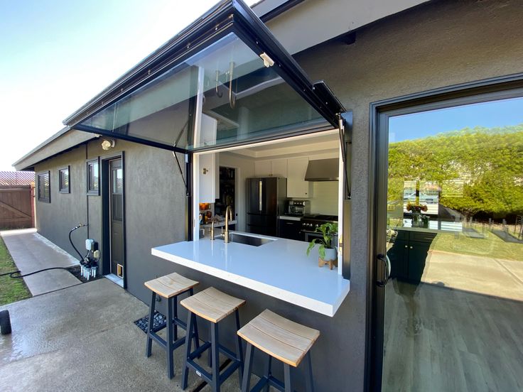 an outdoor kitchen area with stools next to the counter and sliding glass doors leading outside