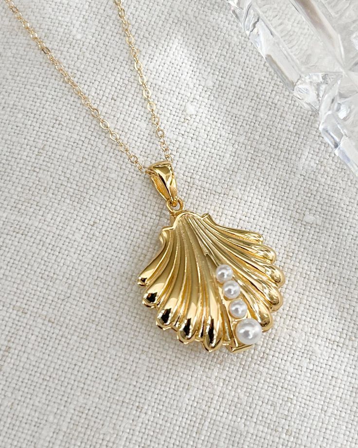 The Shell Locket Necklace with faux pearls. Perfect for the romantic beach get away or beach wedding. An elegant gold plated silver shell 20mm with shell pearls and delicate gold filled chain. All items come in a gift box ready to gift. To see more please visit  https://www.etsy.com/shop/BijouLimon Bijou Limon jewelry collections present a romantic French spin on the latest jewelry trends. Based on the US West Coast but French at heart, Bijou Limon interprets the current jewelry trends and delivers timeless pieces that make you swoon. From Necklaces, Earrings, Bracelets, Rings and more, our Collections are filled with pieces that are both new and nostalgic. Find your unique accessories to complete your look. Personal Insight  What sets me apart? As a small business owner, I'm very consciou Elegant Pearl Pendant Shell For Beach, Pearl Shell Jewelry For Weddings, Elegant Shell Jewelry For Wedding, Wedding Pearl Shell Jewelry, Elegant Shell Necklaces For Wedding, Elegant Pearl Chain Shell For Beach, Gold Shell Jewelry For Weddings, Gold Shell Necklaces For Weddings, Gold Shell Necklace For Wedding