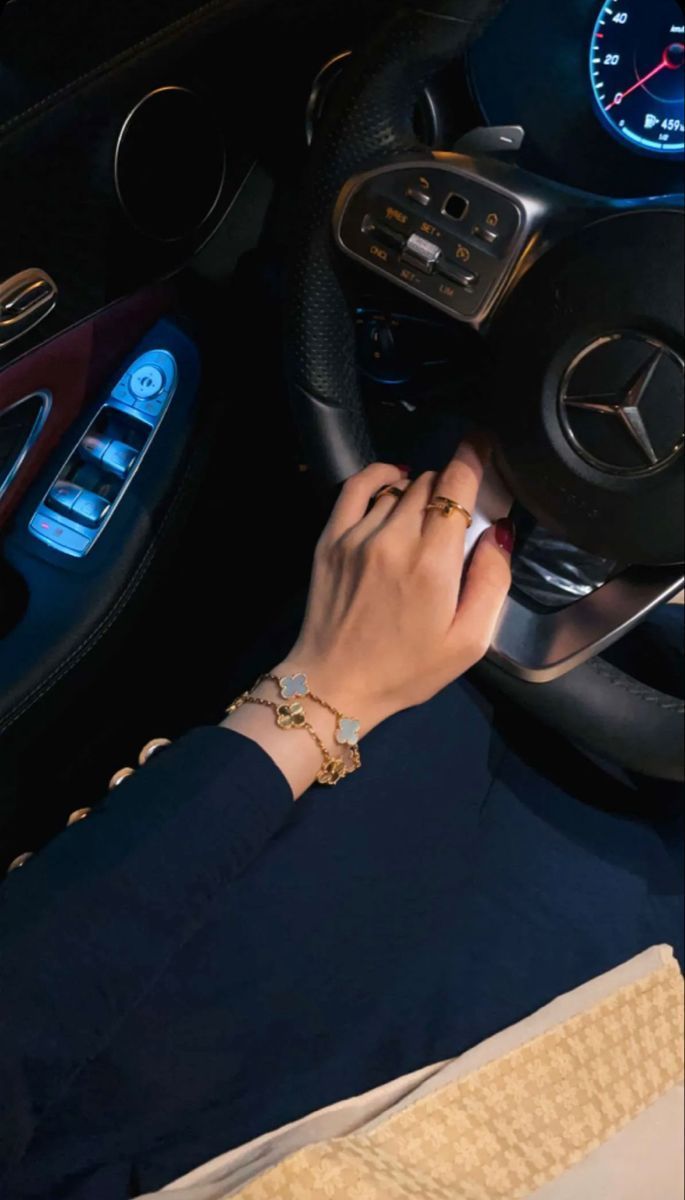 a woman is sitting in the driver's seat of a car with her hand on the steering wheel