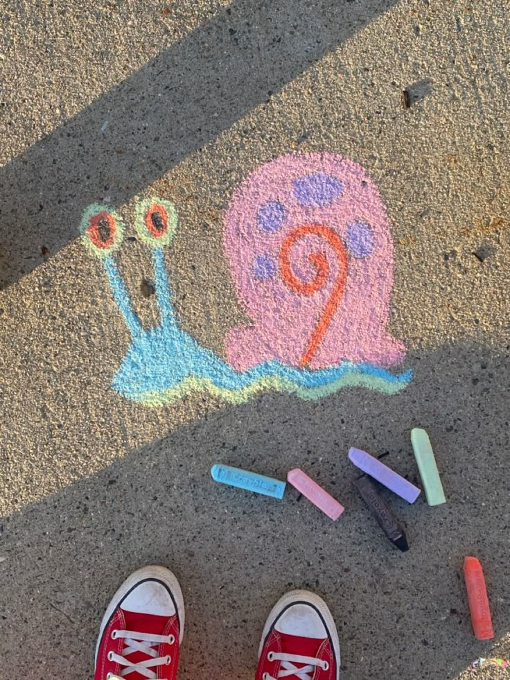 someone's feet are standing on the sidewalk next to crayons and markers