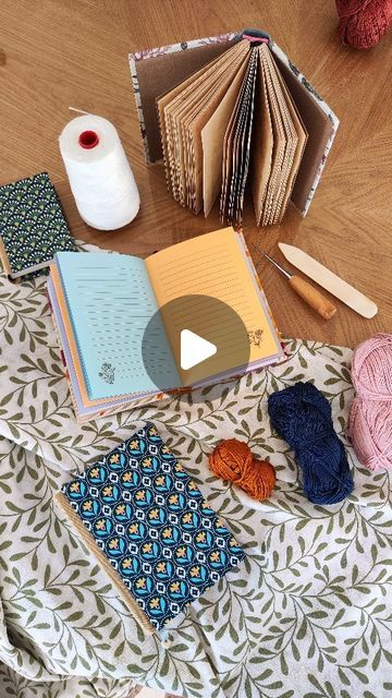 an open book sitting on top of a table next to yarn