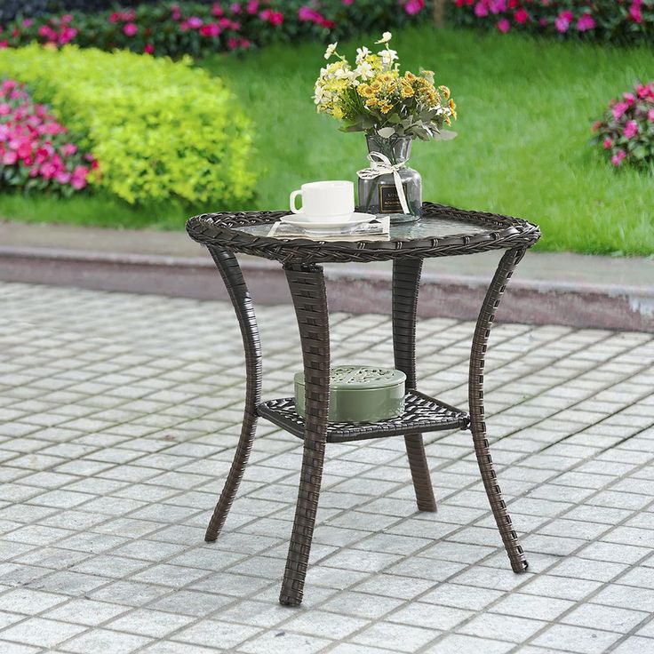 an outdoor table with flowers and a vase on it