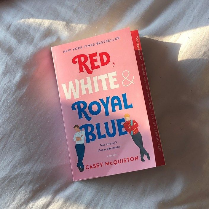 the book red, white and royal blue is laying on a bed