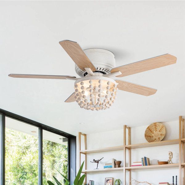 a white ceiling fan in a living room with bookshelves and plants on the shelves