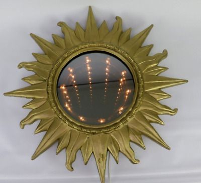 a sun - shaped mirror with lights in the middle is hanging on a white wall