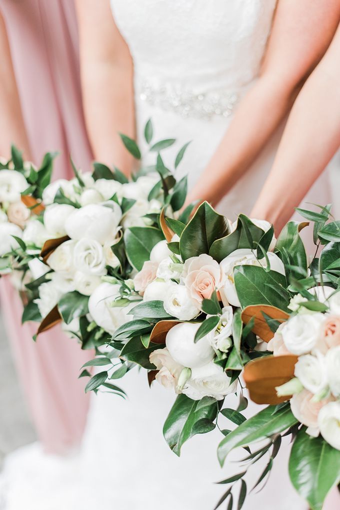 three bridesmaids holding bouquets of white and pink flowers with green leaves on them