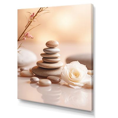 a white rose sitting on top of a pile of rocks next to some stacked stones