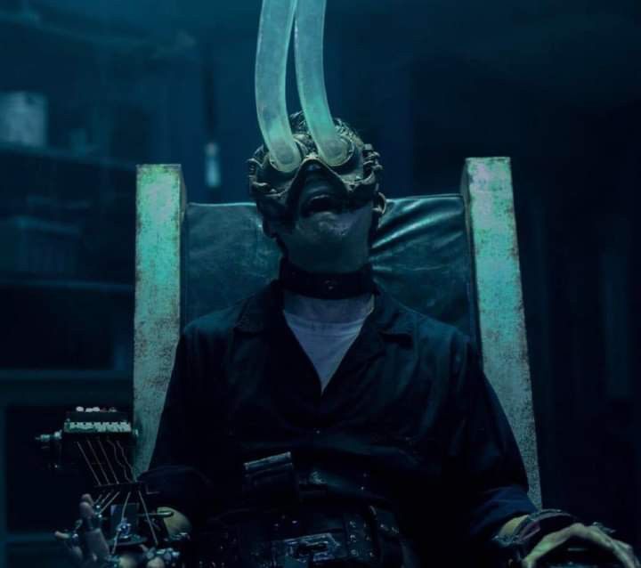 a man sitting in a chair with two horns on his head and an electric guitar