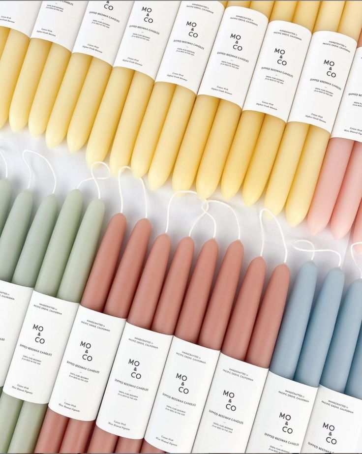 many different colored candles are lined up in the same row and each is labeled with an individual's name