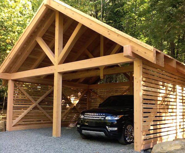 a car is parked in front of a wooden garage with an attached carport and roof