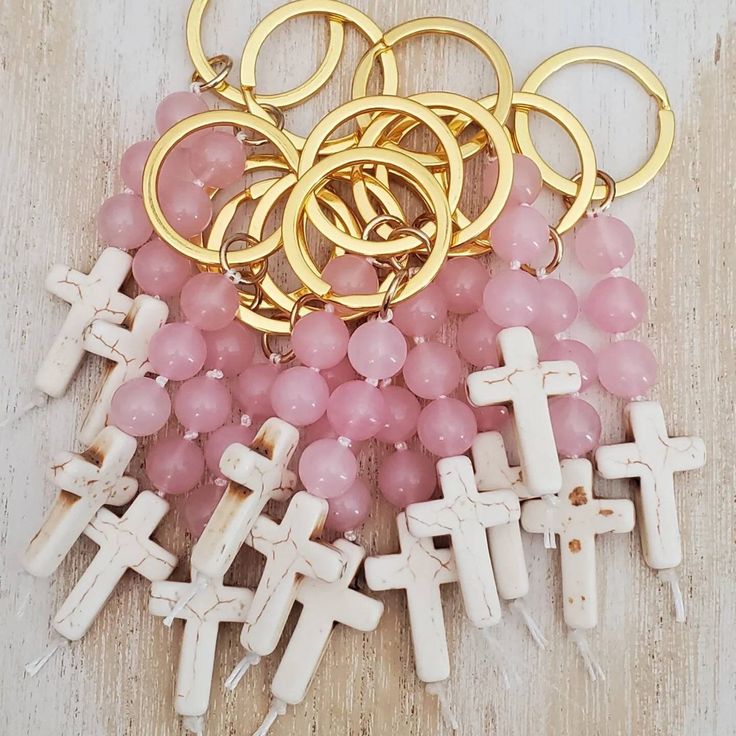 a bunch of crosses and some pink grapes on a wooden table with gold rings around them