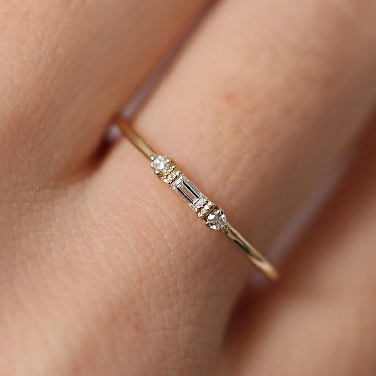 a woman's hand with a diamond ring on top of her finger, showing the side stones